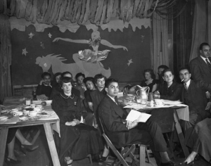 a black and white photograph of a group of students seated around a dining table