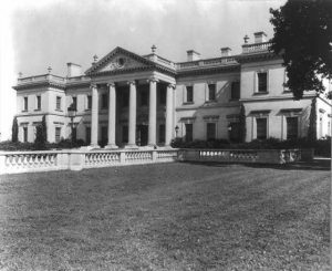 A black and white photograph of a Greek-Revival mansion with a columned portico