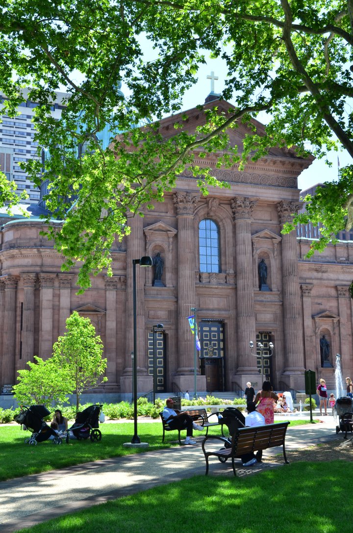 People relaxing outside the Cathedral Basilica of Saints Peter and Paul on a summer day.