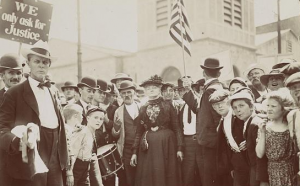 This black and white photograph shows labor activist Mother Jones surrounded by a large group of child textile workers and their parents.