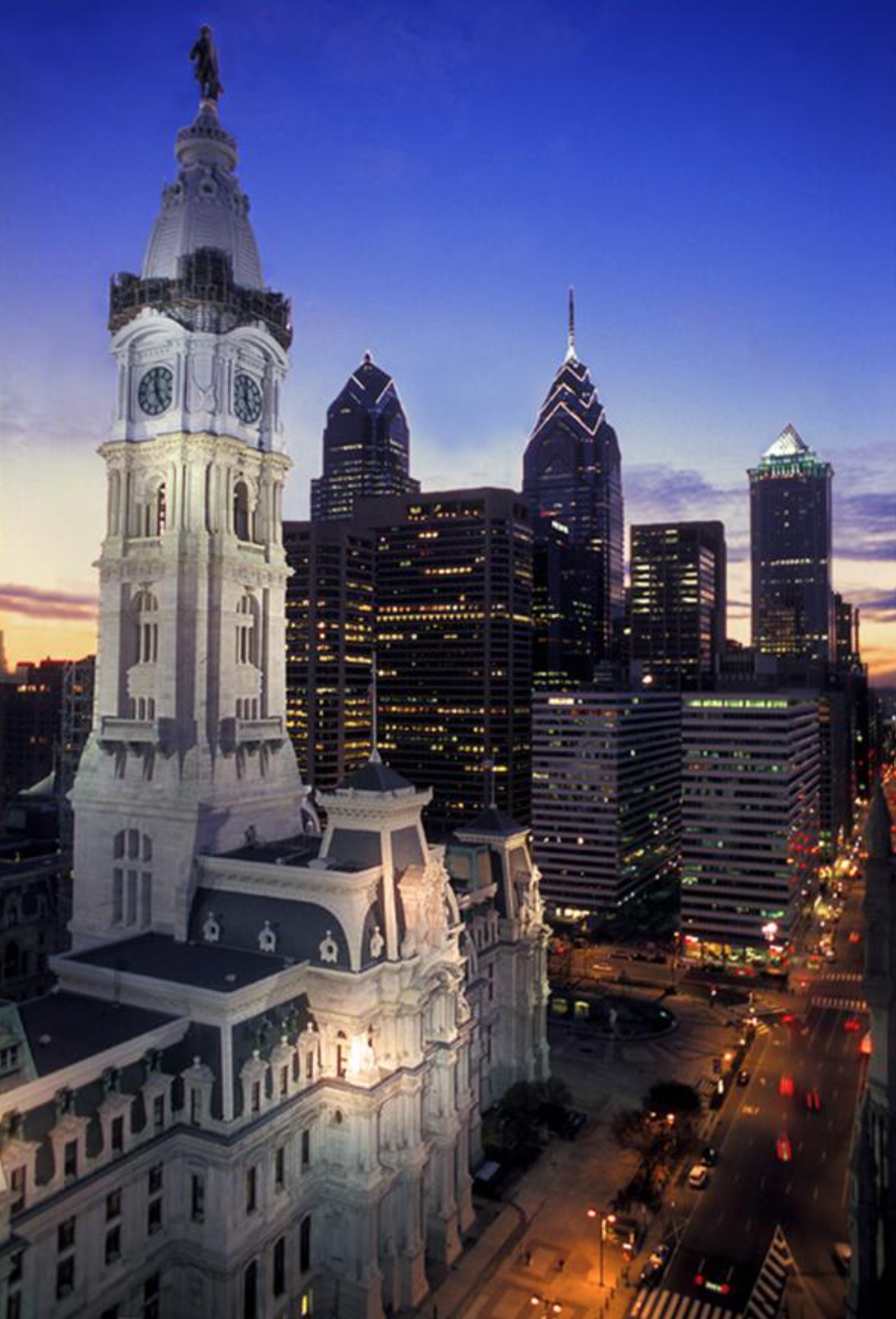 This color photograph shows City Hall circa 2005. Three of Philadelphia's tallest skyscrapers can be seen in the background, illuminated by a sunset.