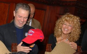 This color photograph shows film director Jonathan Demme and Greater Philadelphia Film Office director Sharon Pinkenson at a 2008 Phillies event. Demme holds a red hat marked "World Series Champions."