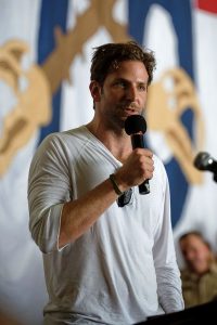 This color photograph shows Bradley Cooper answering a question at a media event.