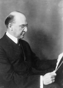 This black and white photograph shows Pierre Samuel du Pont reading a paper. He wears a dark suit and glasses.