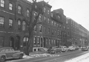 A black and white photograph of a line of three- or four-story row homes on the 600 block of Spruce Street, Philadelphia.