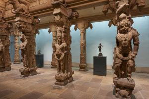 life-sized figures of Indian deities carved into stone pillars with ornate decorations.