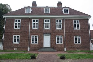 A color photograph of the reconstruction of Pennsbury Manor. It is a three story red brick building with white dormers in the roof.