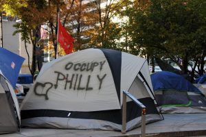 Color photograph showing a camping tent. Spray painted on the side of the tent is Occupy Philly and a heart.