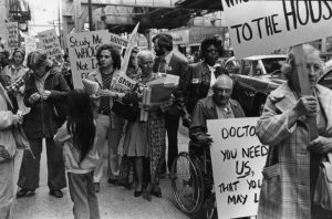 Black and white photograph of a crowd of people holding protest signs.