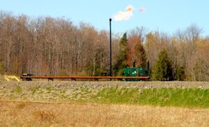 a color photograph of hydraulic fracturing equipment in a field. Flames burn off escaping natural gas from a vent pipe.