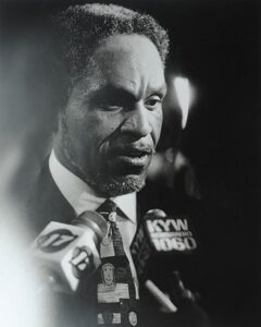 Photo of John F. Street in front of news microphones