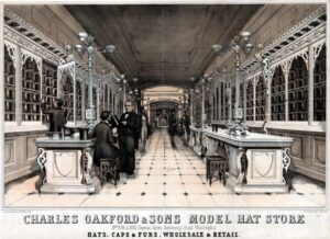 A black and white advertisement for Charles Oakford & Sons Model Hat Store, numbers 826 and 828 Chestnut Street, Continental Hotel, Philadelphia. The store is a long, narrow space with ornate cases full of men's hats lining the walls with counters and seats in front of them. A customer is seated at one counter while the proprietor shows him a top hat. Other customers and employees interact in the background.