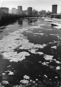 foamy substance on surface of river in black and white photo