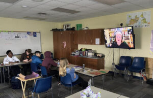 Photograph of students with speaker on video screen