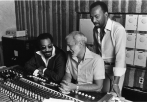 Three men are photographed producing using a mixing board.