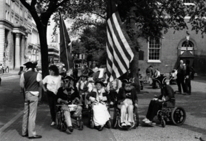 black and white photograph of wheelchair-using protesters dressed in colonial costumes in the streets of philadelphia