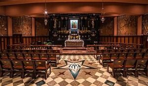 Decorated interior of a shrine with chairs facing an altar.